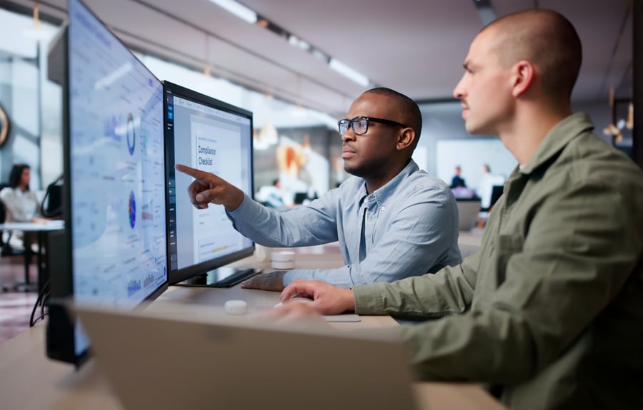 A coworker showing another coworker something on a large computer monitor