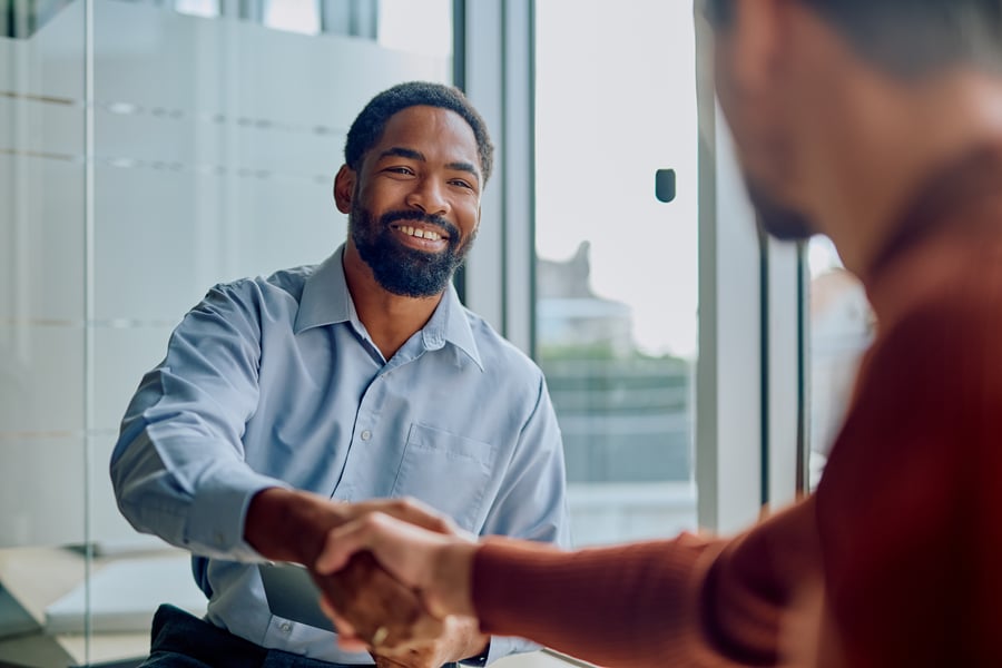 A man smiling and shaking hands with someone in an office