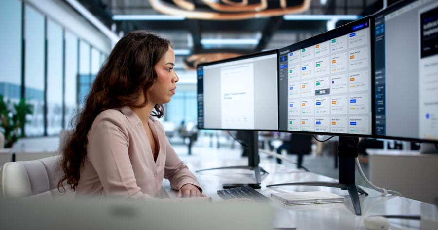 A woman in an office looking at business credit data on three monitors