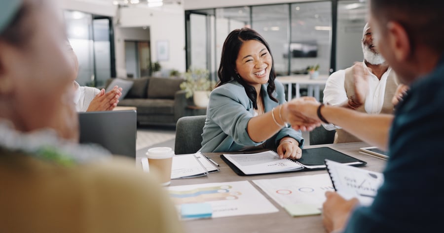 A woman smiling and shaking hands with a business partner