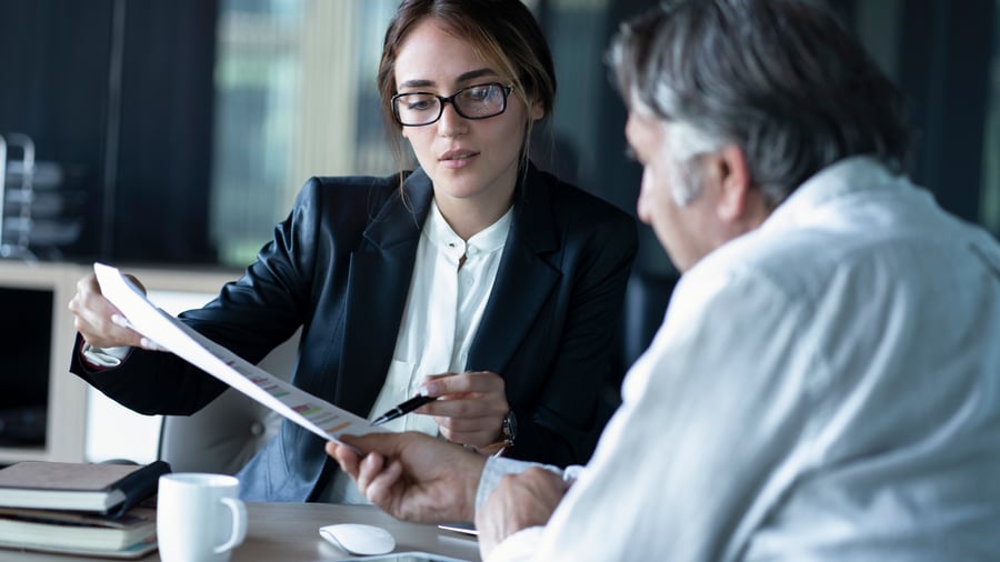 A woman showing a man something on a piece of paper in an office