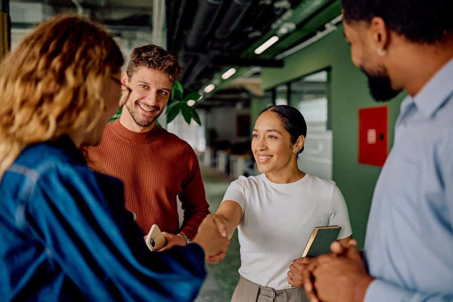 A woman shaking hands with another woman in a casual office setting