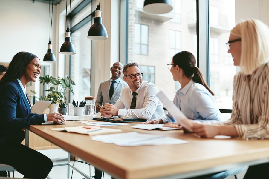 A group of coworkers smiling at each other during a meeting in a modern office