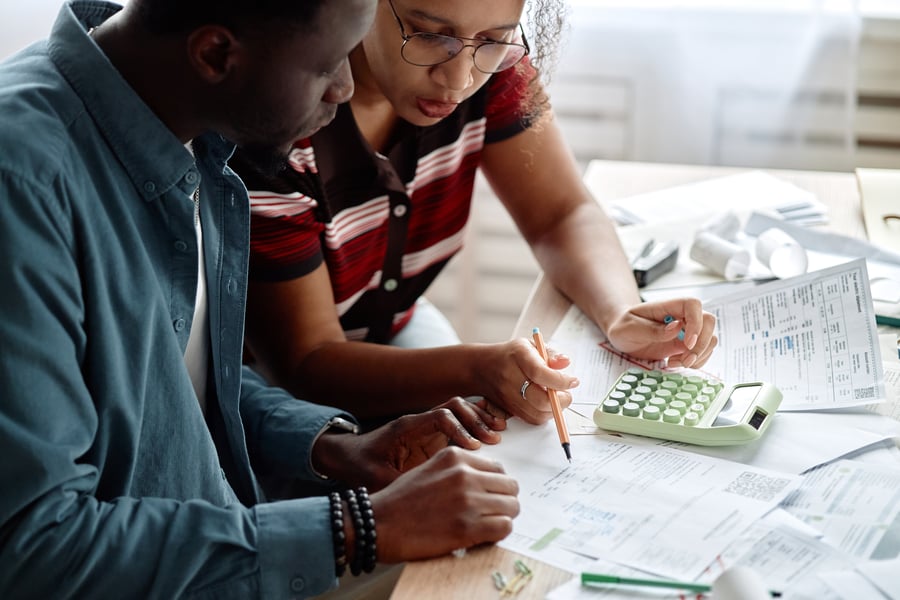 Two coworkers going over numbers surrounded by paperwork and a calculator