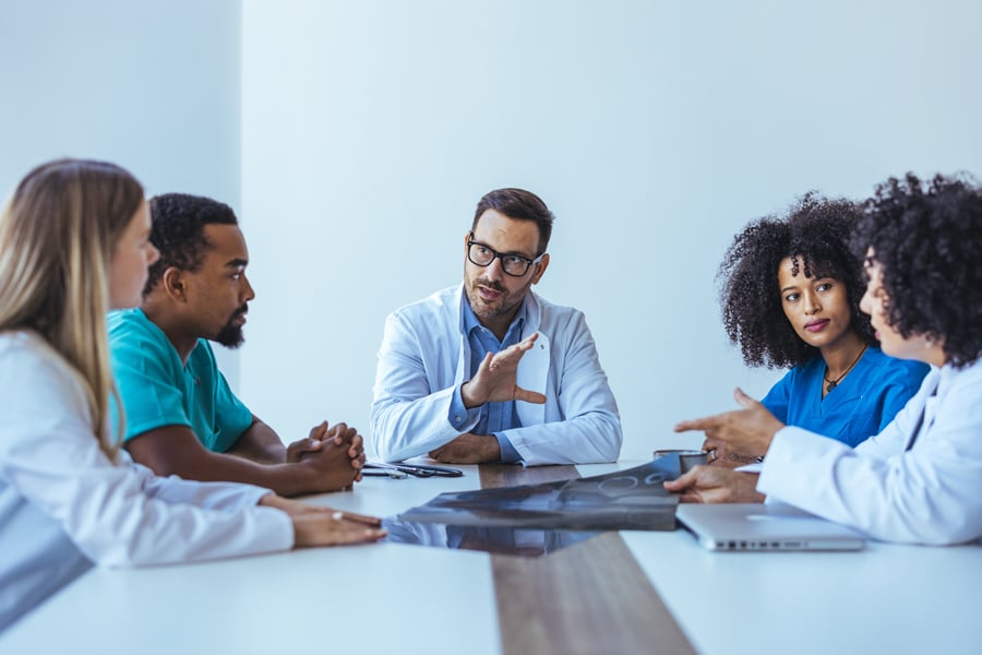 A man presenting something at the head of a boardroom table in an office