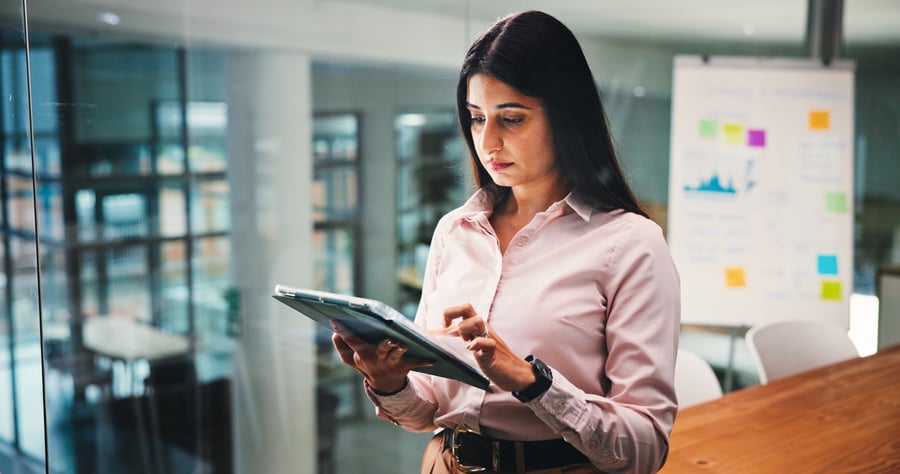 A woman assessing something on a tablet in the middle of a modern office