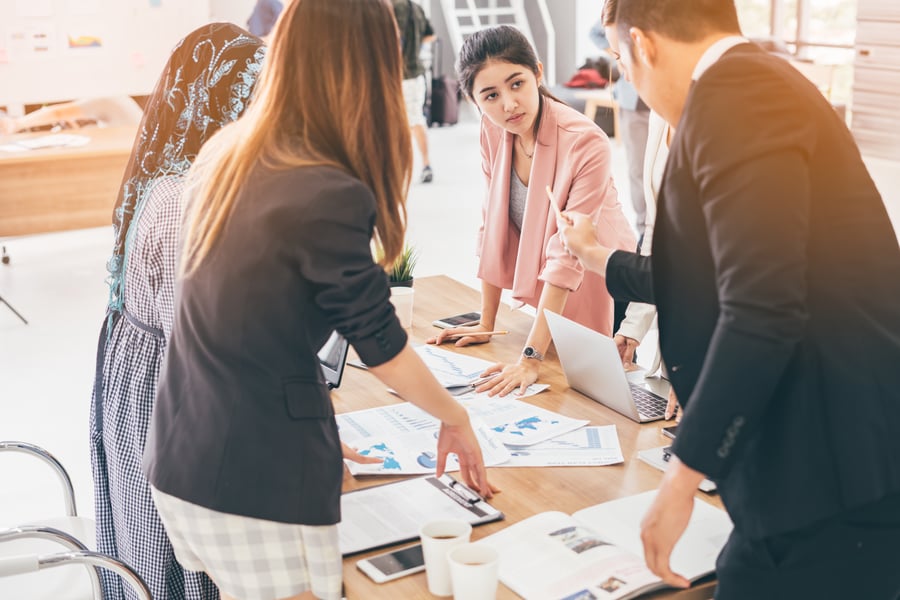 A team standing around a table in an office, going over paperwork