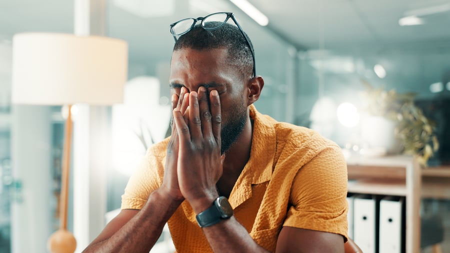 A man rubbing his face looking frustrated with late payments in an office