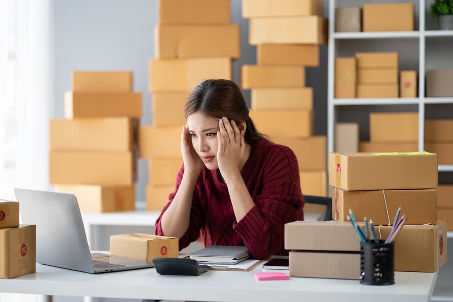 A woman surrounded by boxes looking worried