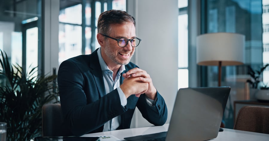 A smiling businessman looking at his laptop