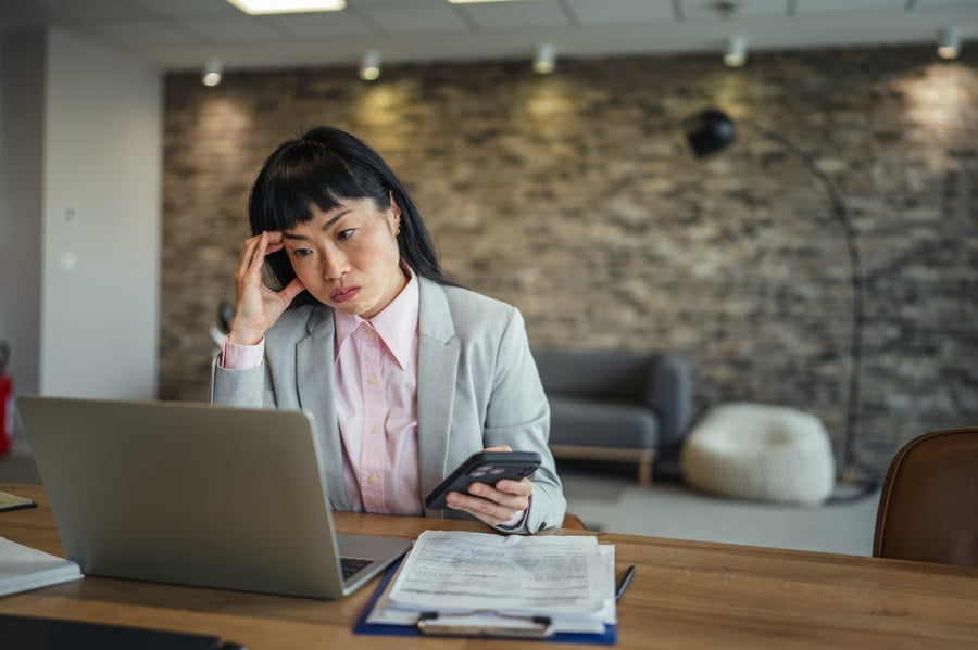 A woman looking concerned looking at her laptop in an office