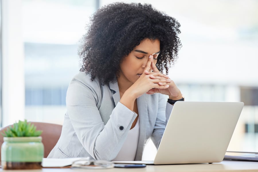 A woman looking frustrated/upset in an office at something on her laptop screen