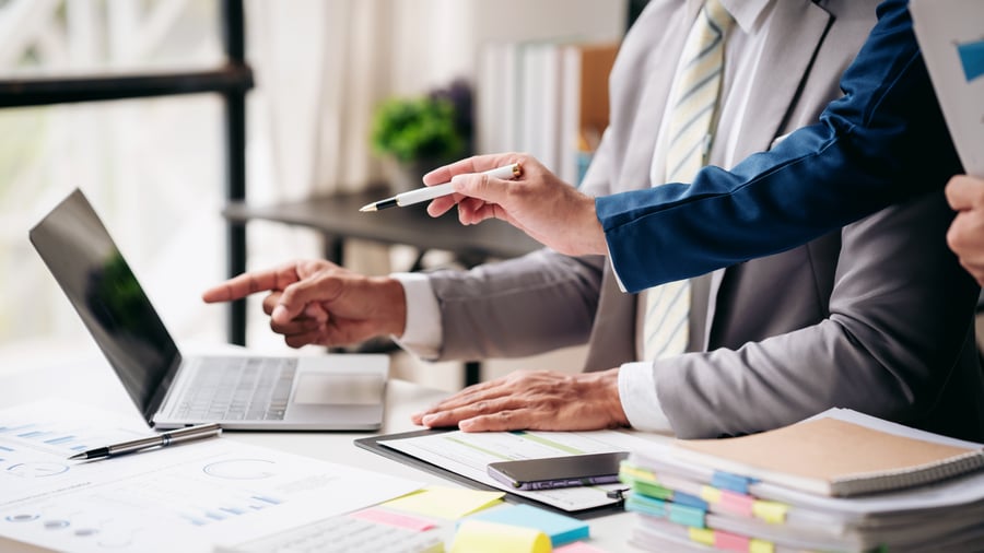 People pointing at something on a laptop screen in an office