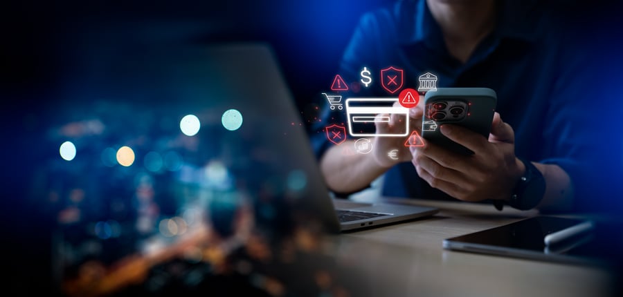A businessperson holding their phone with a credit card graphic overlaid - a warning about b2b fraud