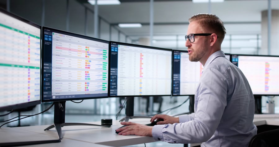 A man looking at several monitors containing credit risk data to prevent b2b fraud