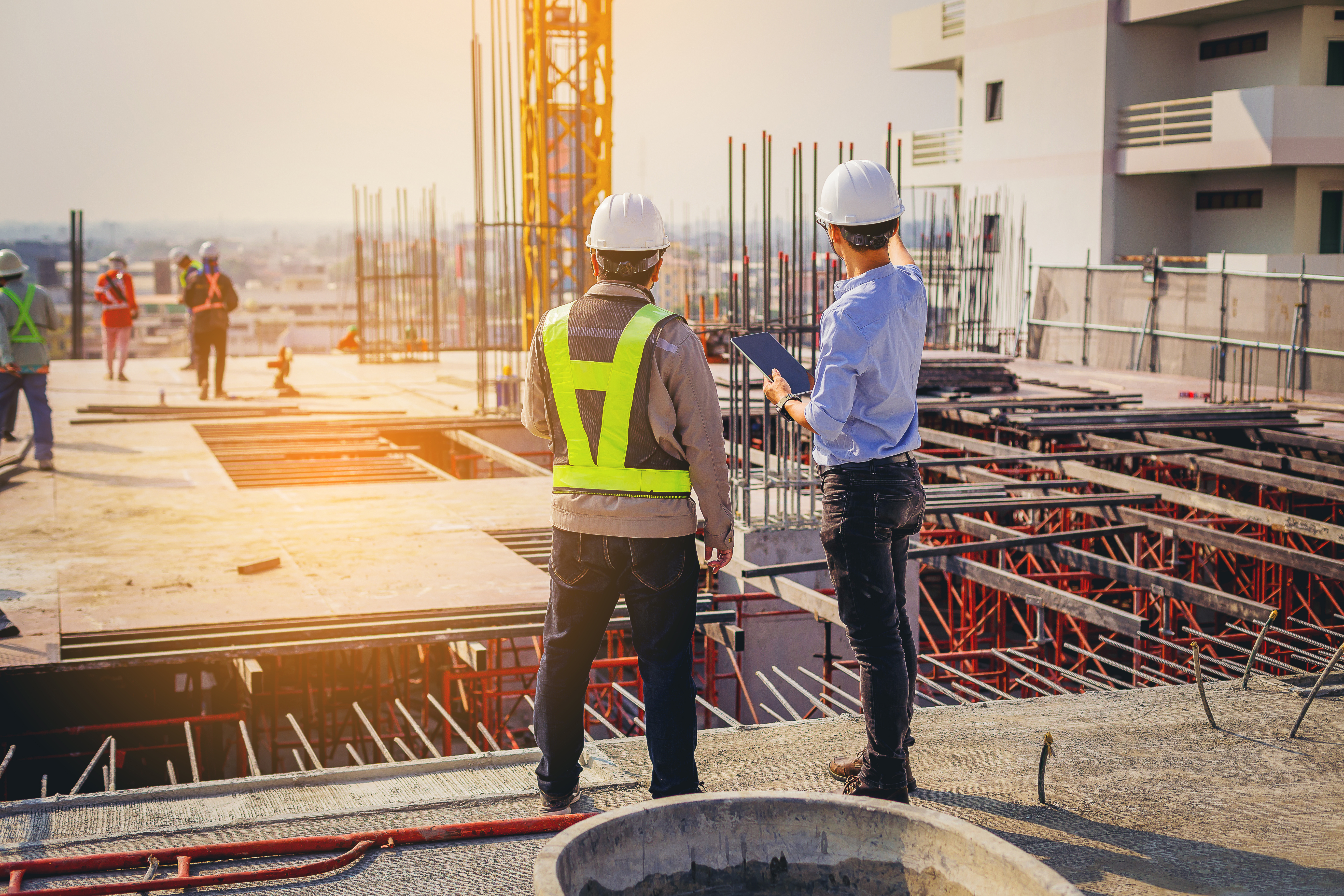 Two people standing in a construction site, consulting blueprints