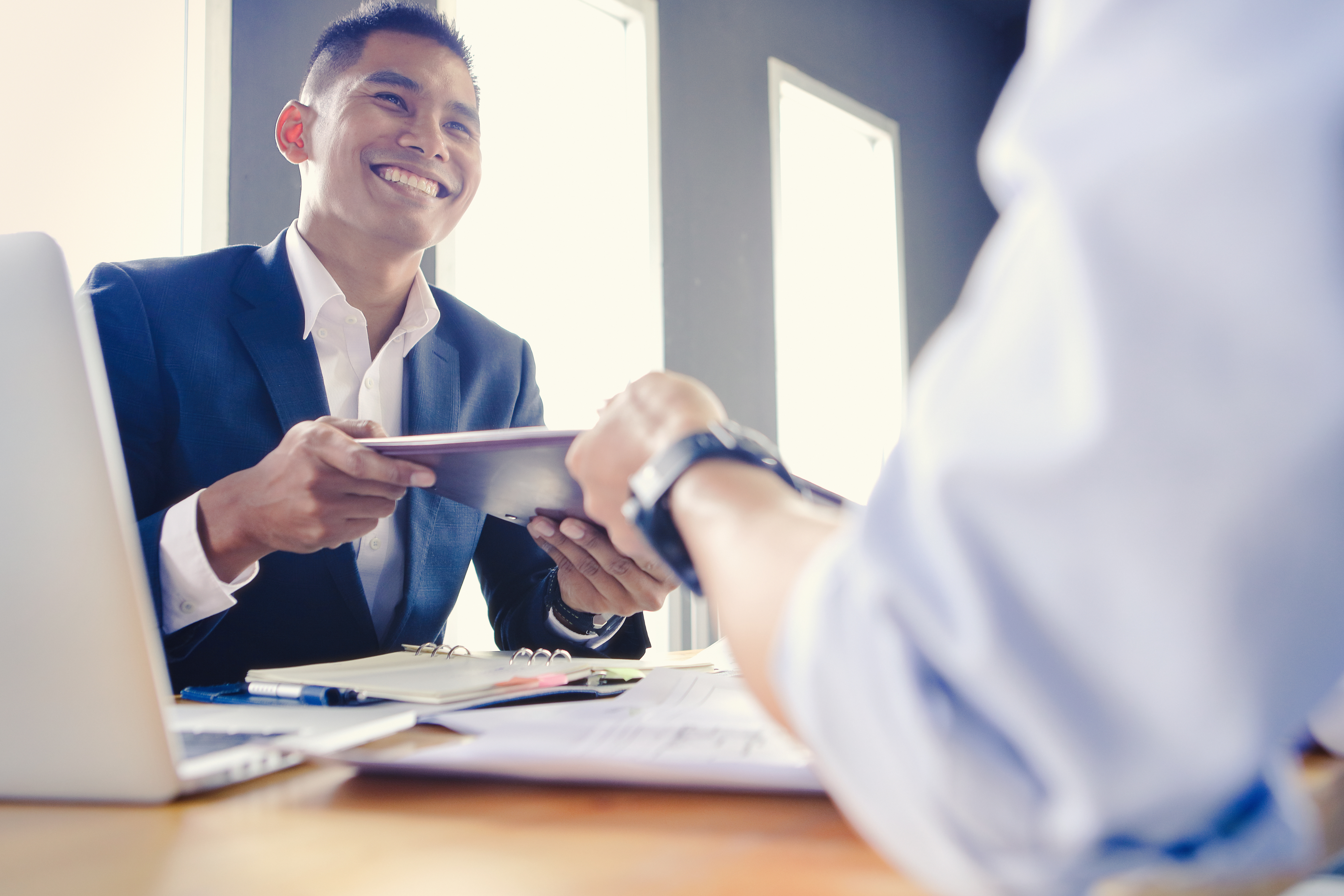 A man passing a tablet to someone else in a business setting