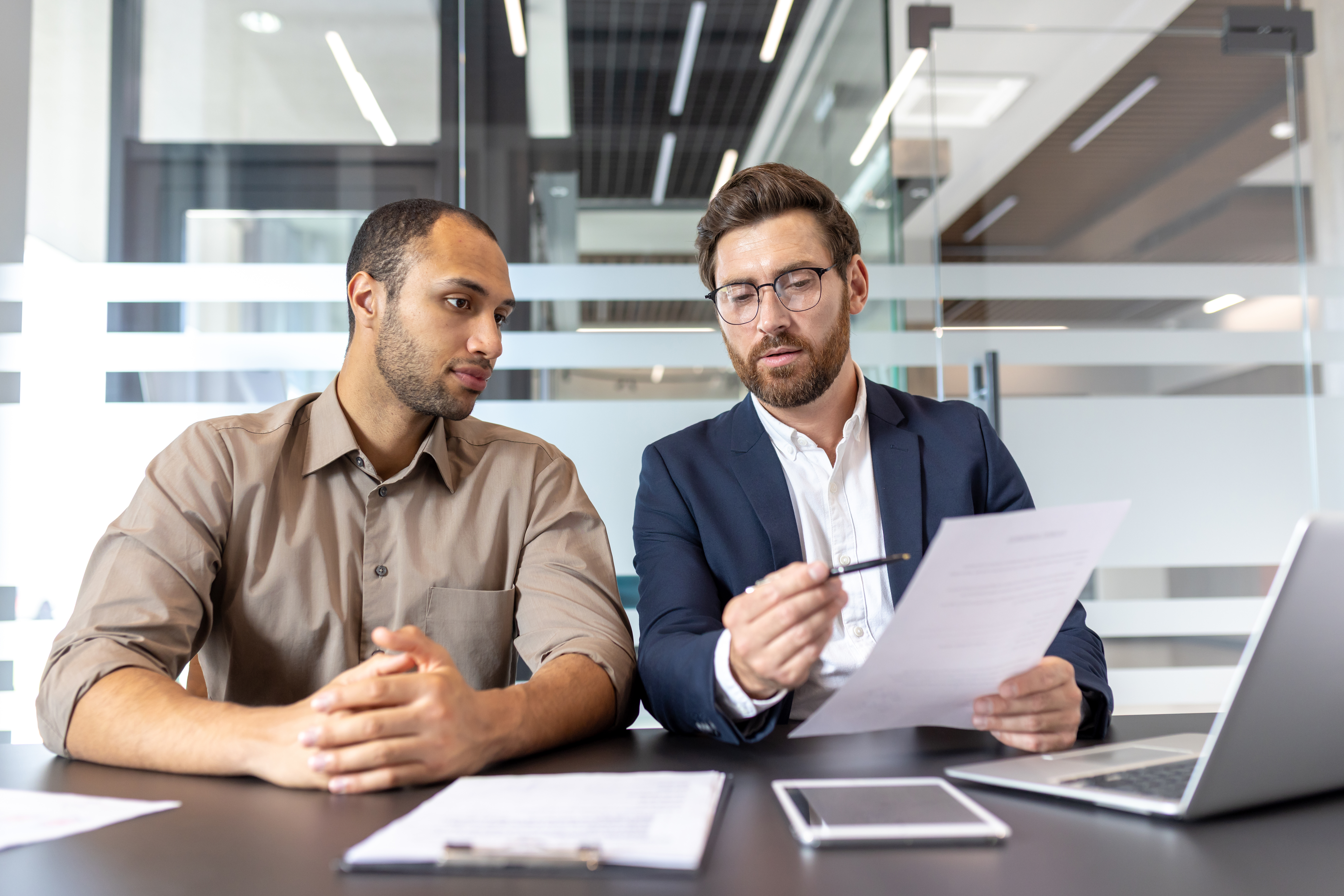 Two businessmen consulting a report in an office
