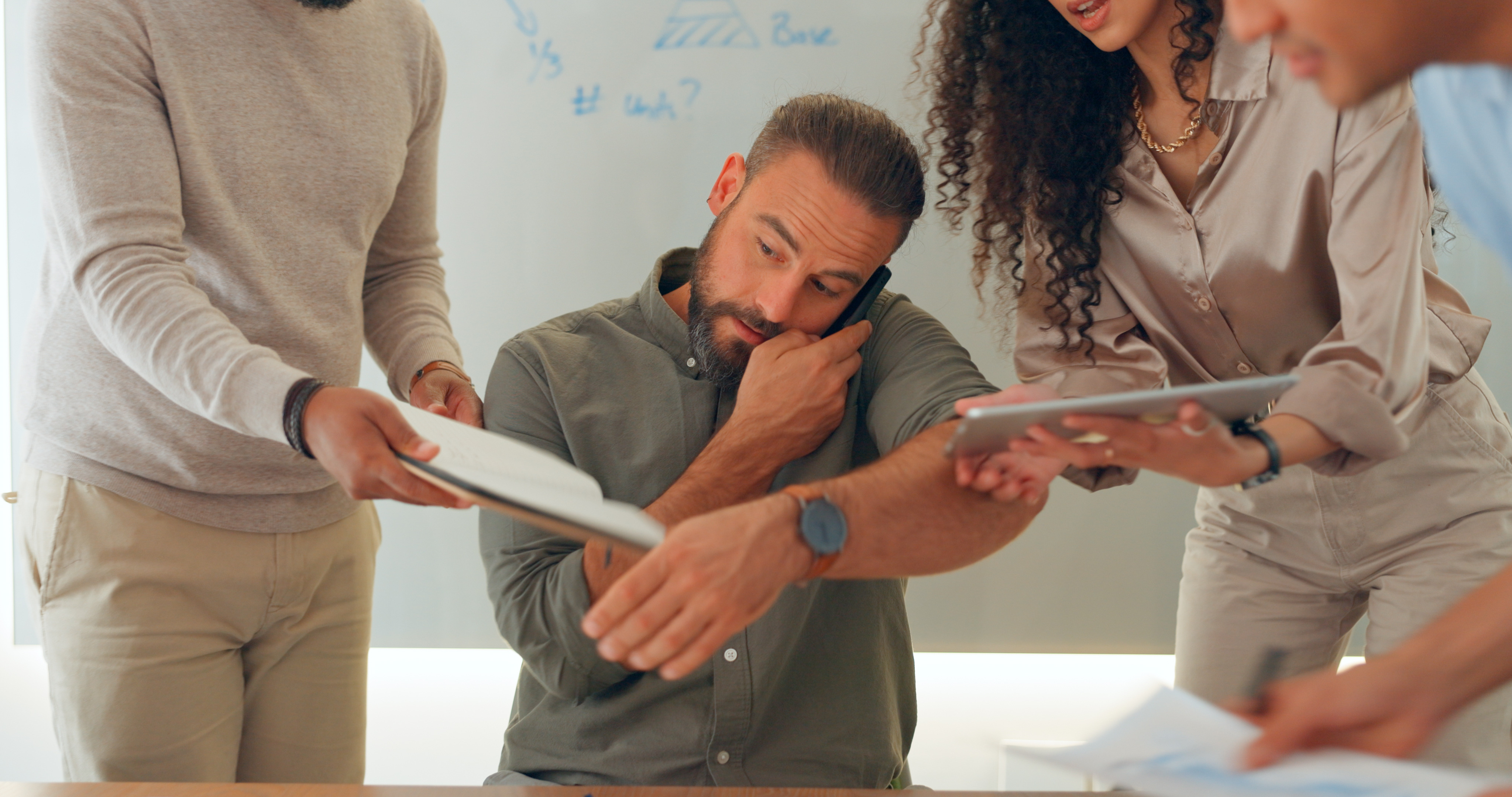 A busy man being faced with multiple people holding paperwork and tablets